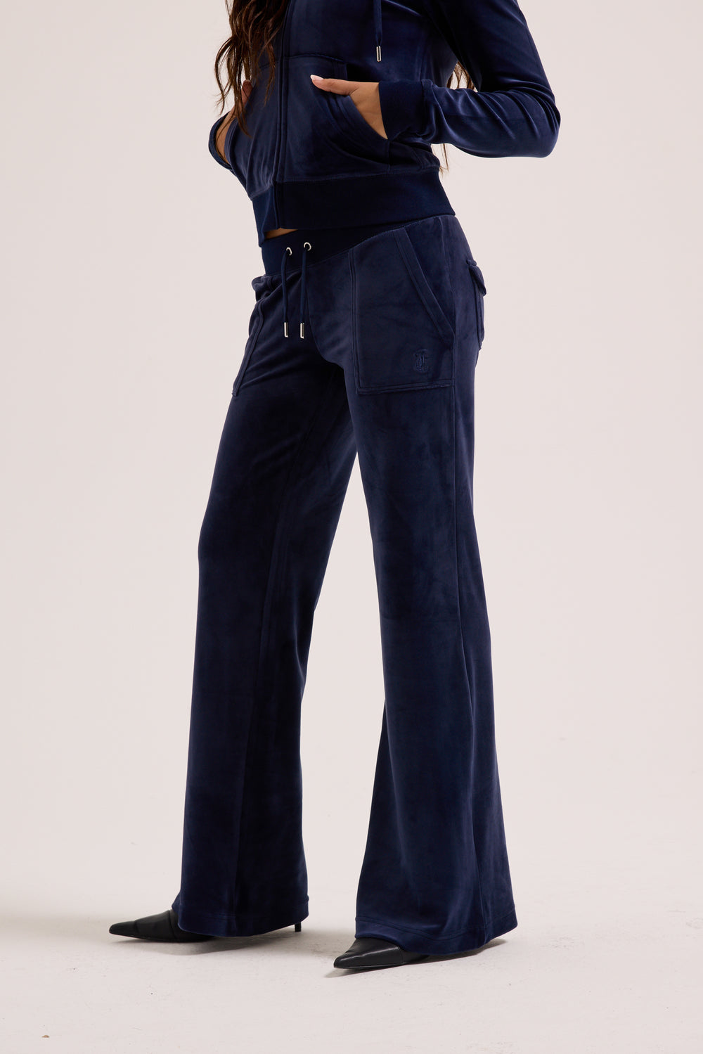 Displays a model wearing the Night Sky 'Juicy' branded low rise velour track pants 