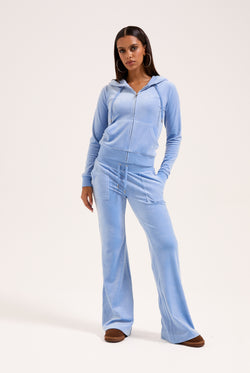Displays a model wearing the Della Robia 'Juicy' branded low rise flare classic velour track pant 