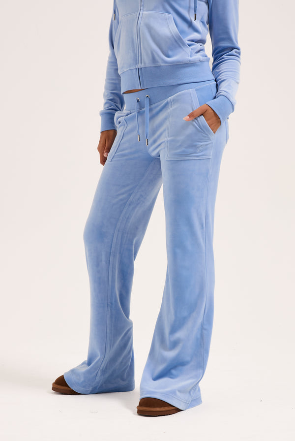 Displays a model wearing the Della Robia 'Juicy' branded low rise flare classic velour track pant 