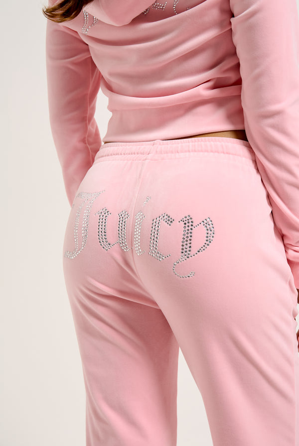 Displays a model wearing the Juicy Pink 'Juicy' branded velour diamanté tracksuit bottoms 