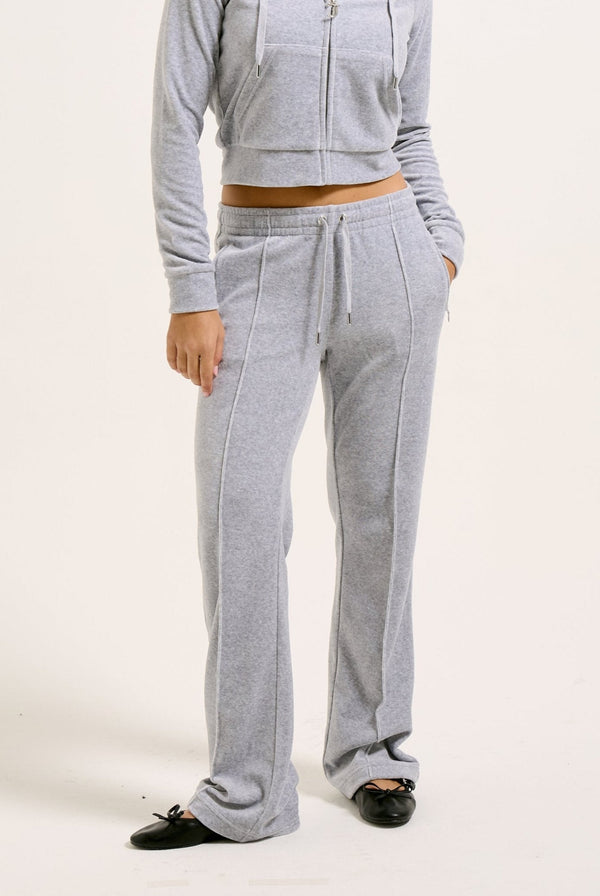 Displays a model wearing the Silver Marl Diamanté 'Juicy' branded cotton velour tracksuit bottom  