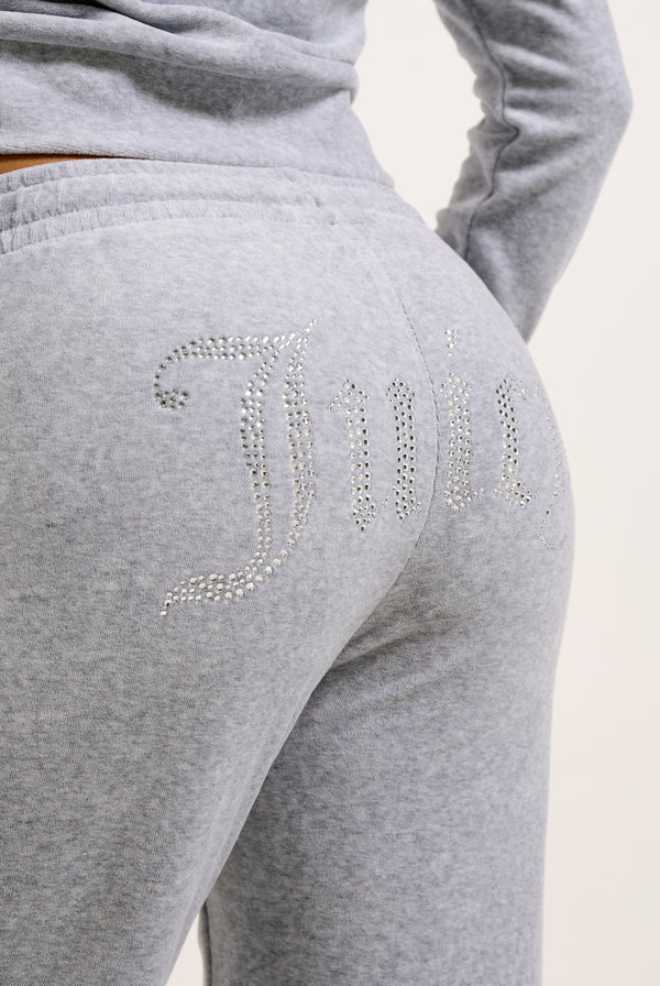 Displays a model wearing the Silver Marl Diamanté 'Juicy' branded cotton velour tracksuit bottom  