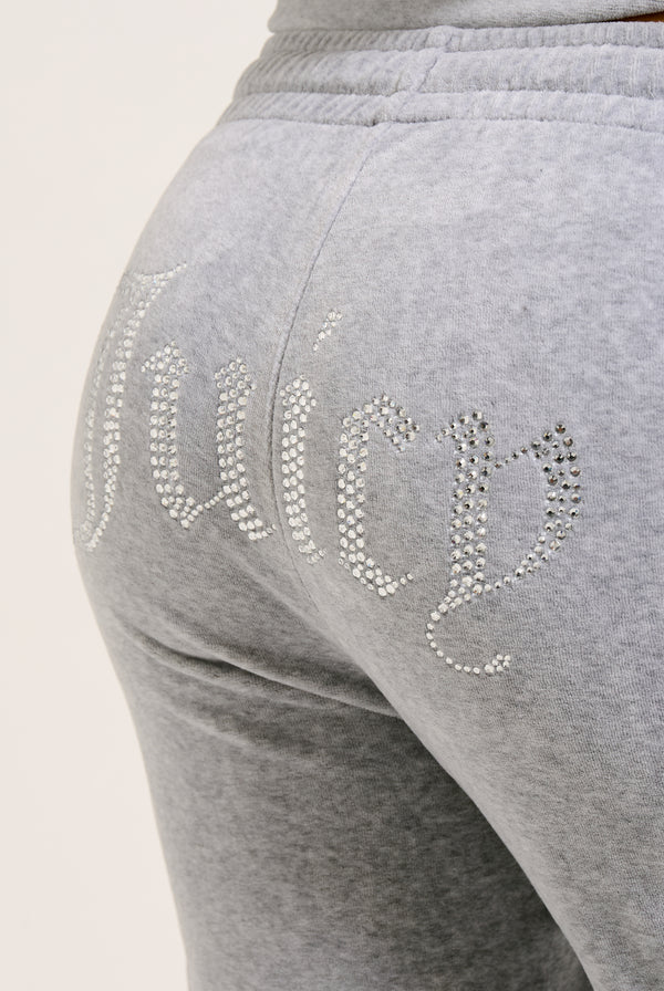 Displays a model wearing the Silver Marl Diamanté 'Juicy' branded cotton velour tracksuit bottom  