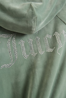 Displays a model wearing the Chinois Green 'Juicy' branded diamanté velour zip-through hoodie featuring the juicy branding 