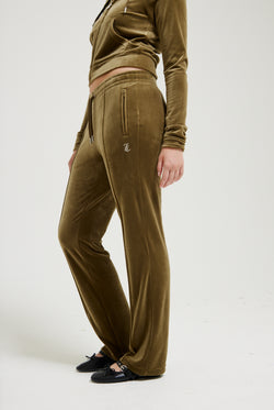 Displays a model wearing the Dark Olive 'Juicy' branded velour diamanté tracksuit bottom