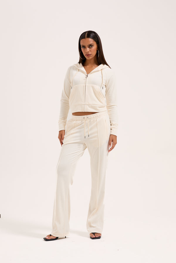 Displays a model wearing the cream 'juicy' branded cream outline diamanté velour zip-through hoodie 