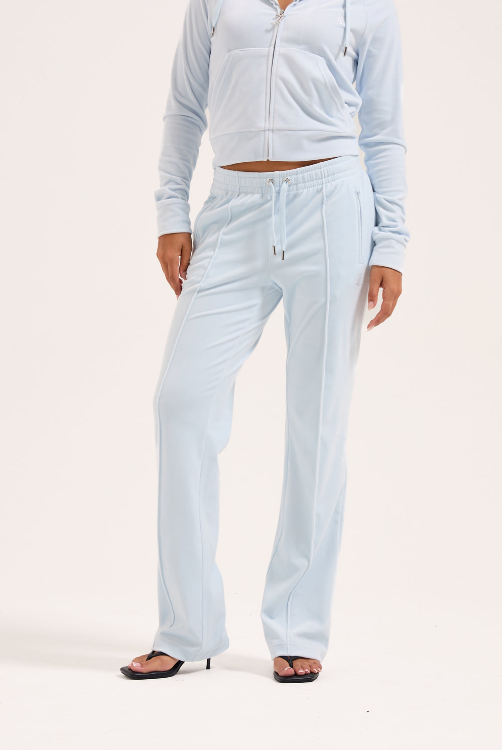 Displays a model wearing the Nantucket Breeze 'Juicy' branded velour outline diamanté tracksuit bottom 