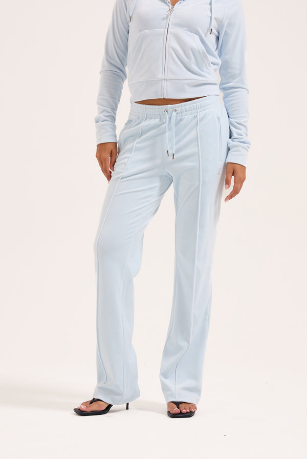 Displays a model wearing the Nantucket Breeze 'Juicy' branded velour outline diamanté tracksuit bottom 