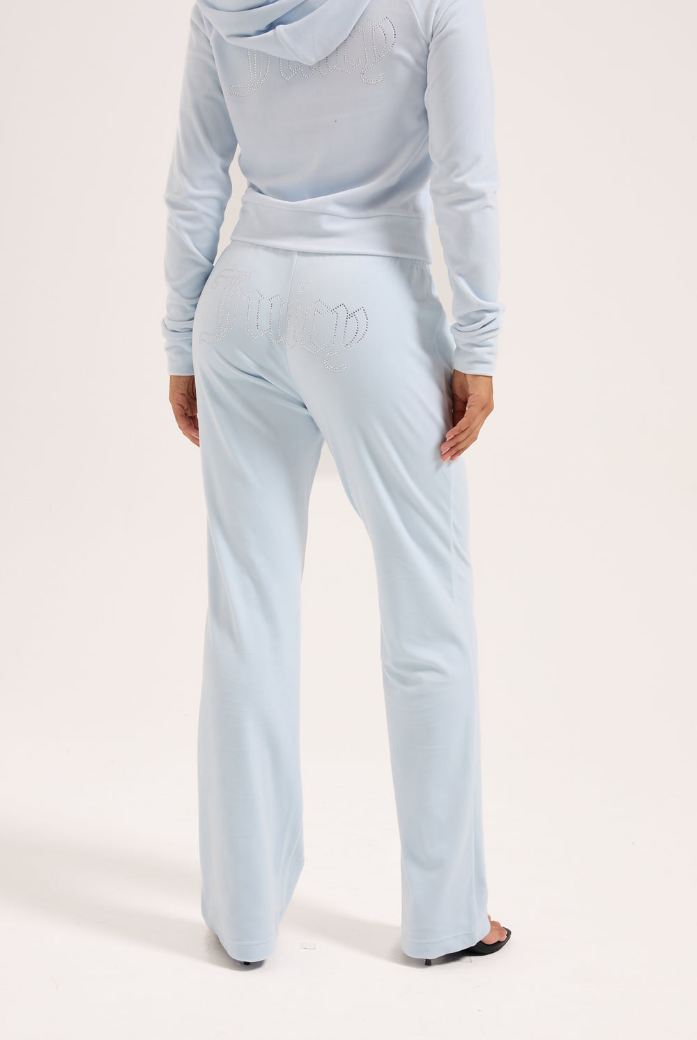 Displays a model wearing the Nantucket Breeze 'Juicy' branded velour outline diamanté tracksuit bottom 