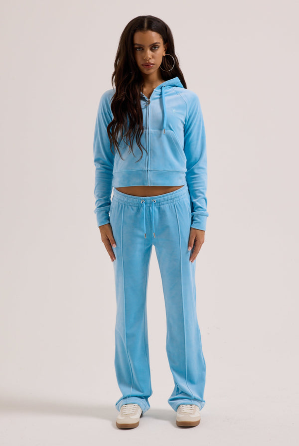 Displays a model wearing the sky blue outline 'juicy' branded velour zip-through hoodie 