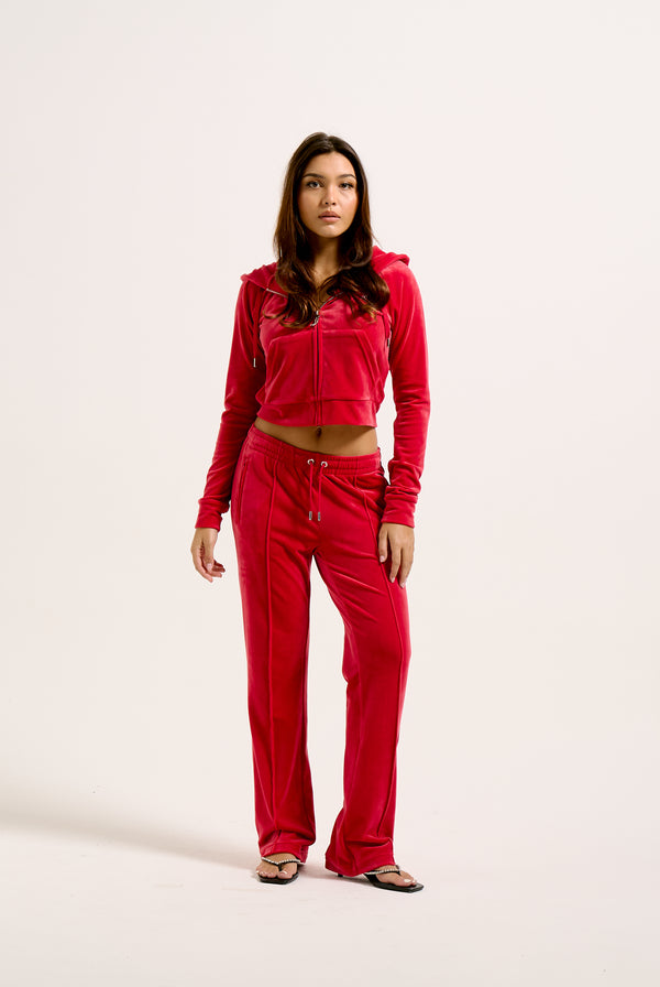 Displays a model wearing the Astor Red Velour 'Juicy' branded Diamanté tracksuit bottoms with the matching top