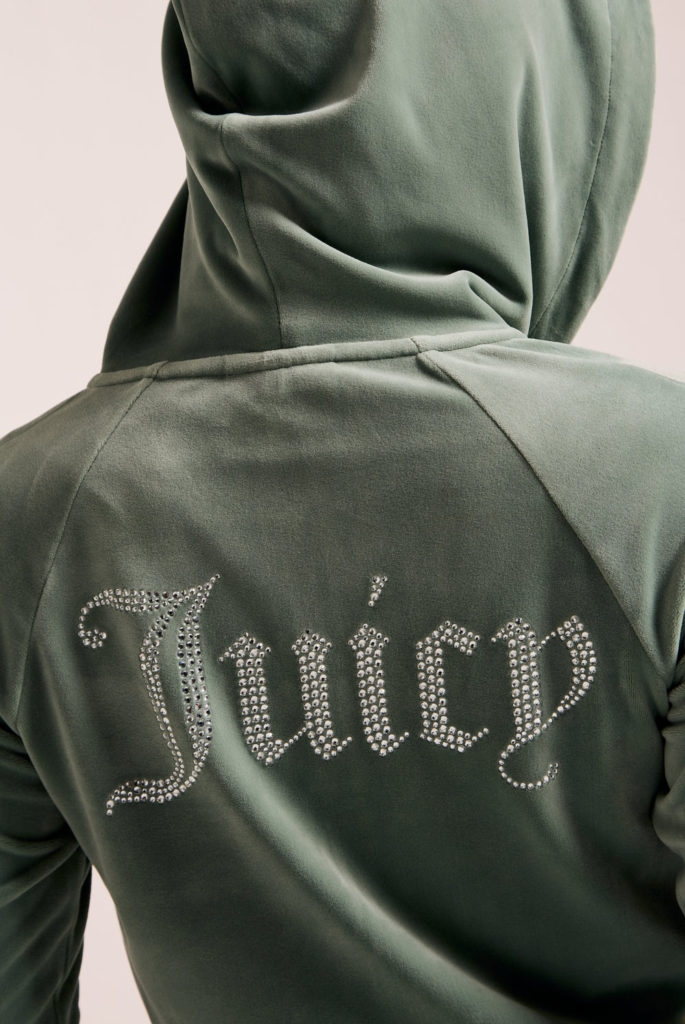 Displays a model wearing the Chinois Green 'Juicy' branded diamanté velour zip-through hoodie featuring the juicy branding 