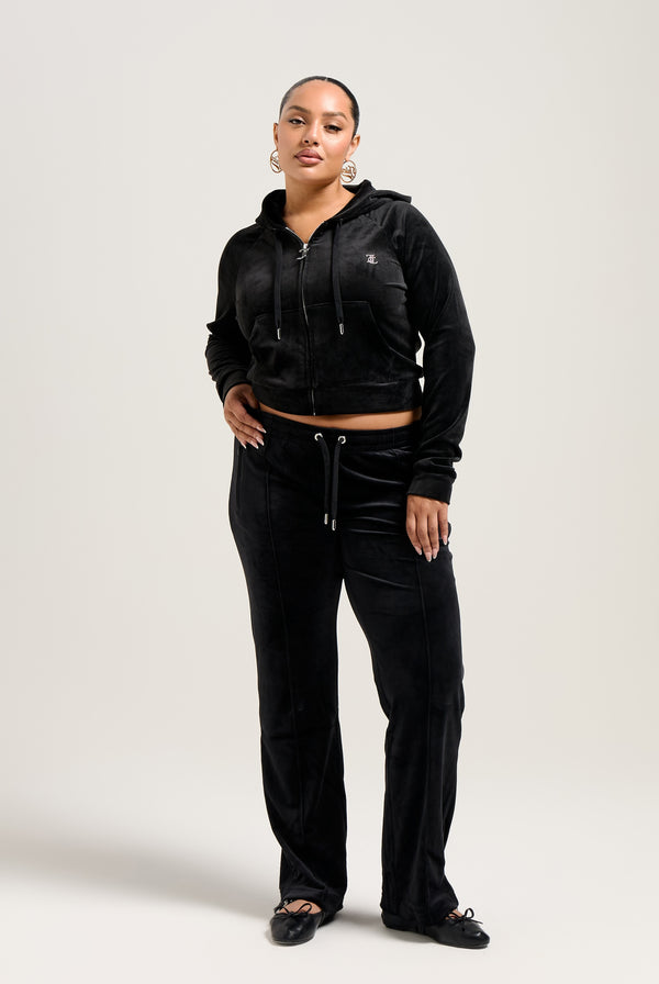 Woman wearing Black velour tracksuit with diamante embellishments, mid-rise fit, and adjustable drawstring waist.