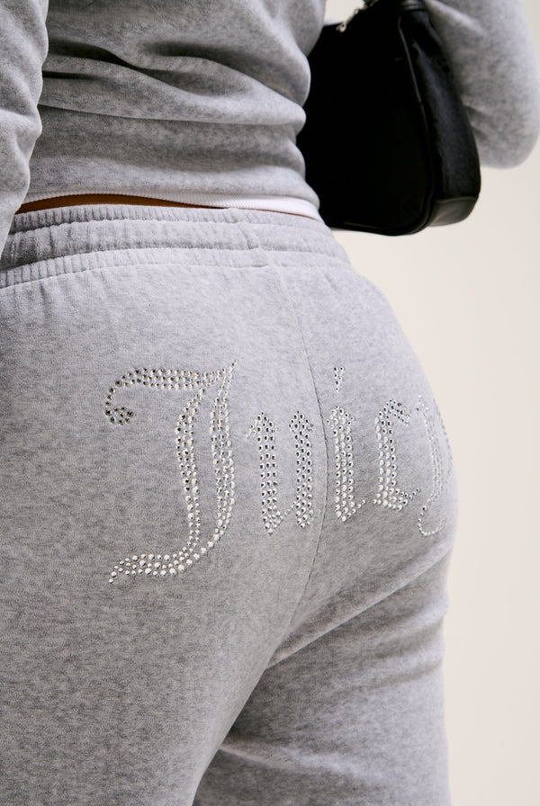 Displays a model wearing the Silver Marl Diamanté 'Juicy' branded cotton velour tracksuit bottom  