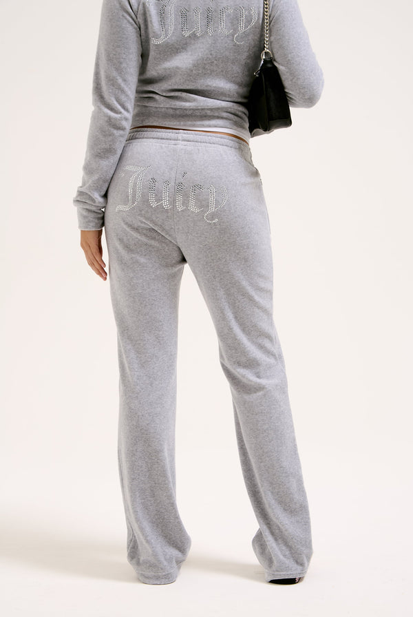 Displays a model wearing the Silver Marl Diamanté 'Juicy' branded cotton velour tracksuit bottom  