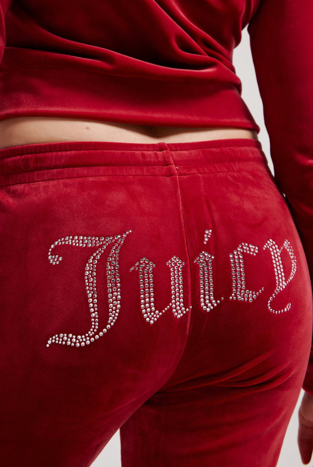 Displays a model wearing the Red Dahlia 'Juicy' branded velour diamanté tracksuit bottom featuring the juicy branding 