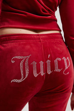Displays a model wearing the Red Dahlia 'Juicy' branded velour diamanté tracksuit bottom featuring the juicy branding 