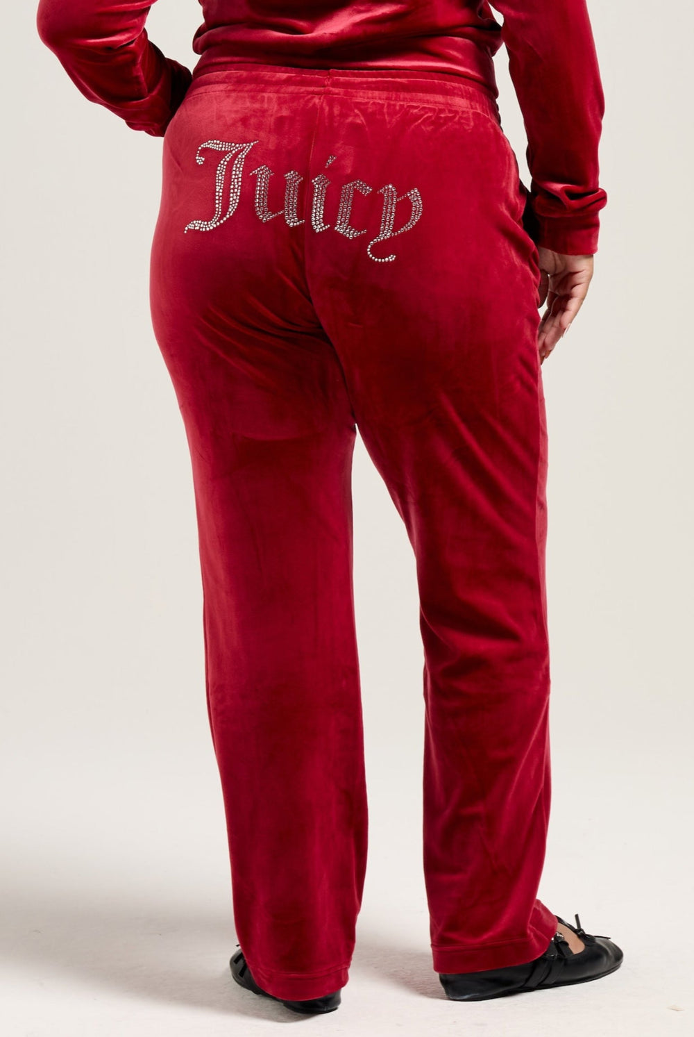 Displays a model wearing the Red Dahlia 'Juicy' branded velour diamanté tracksuit bottom