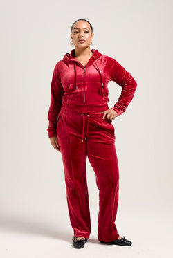 Displays a model wearing the Red Dahlia 'Juicy' branded velour diamanté tracksuit bottom
