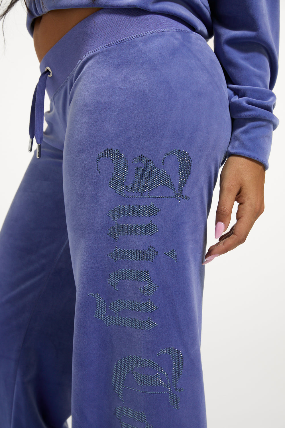 Displays a model wearing the Greyblue 'Juicy' branded Old Gothic Diamante OG Straight Leg Trackpant featuring the details on the juicy branding 