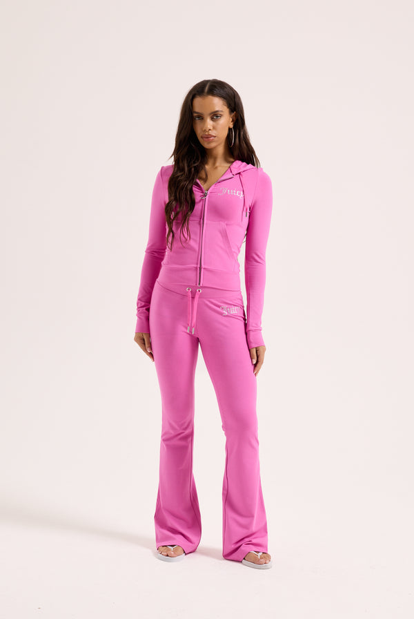 Displays a model wearing the super pink 'juicy' branded diamanté luxury jersey low rise pant 