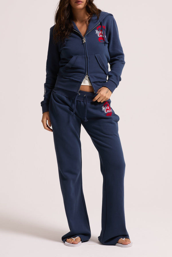 Displays a model wearing the Mood indigo relaxed fit 'juicy' branded flare fleece track pant 