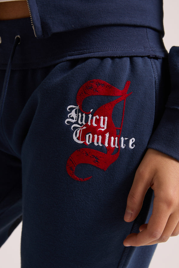 Displays a model wearing the Mood indigo relaxed fit 'juicy' branded flare fleece track pant featuring the juicy Couture logo