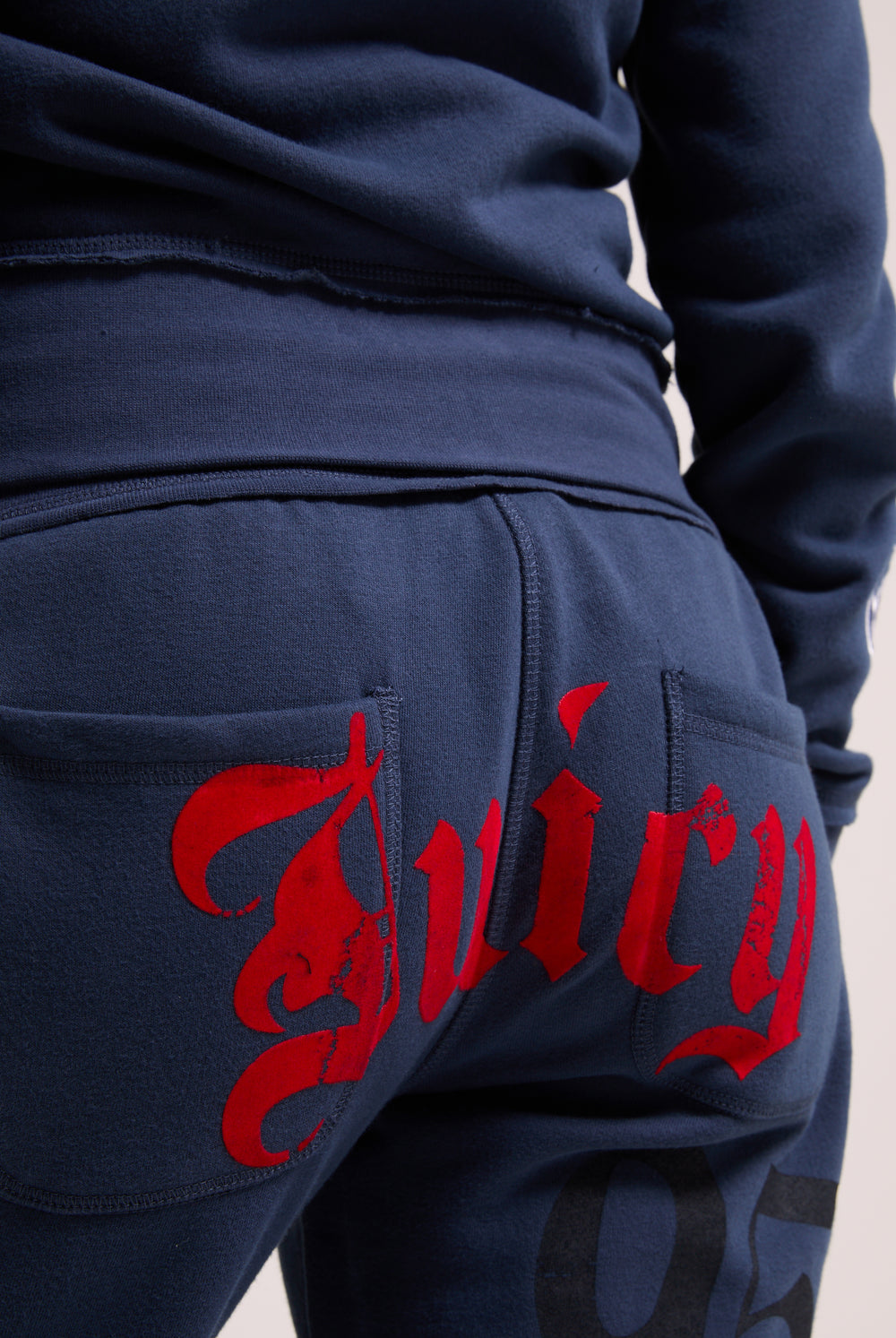Displays a model wearing the Mood indigo relaxed fit 'juicy' branded flare fleece track pant featuring the juicy branding 