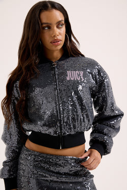 Displays a model wearing the 'juicy' branded choose juicy sequin cropped bomber 