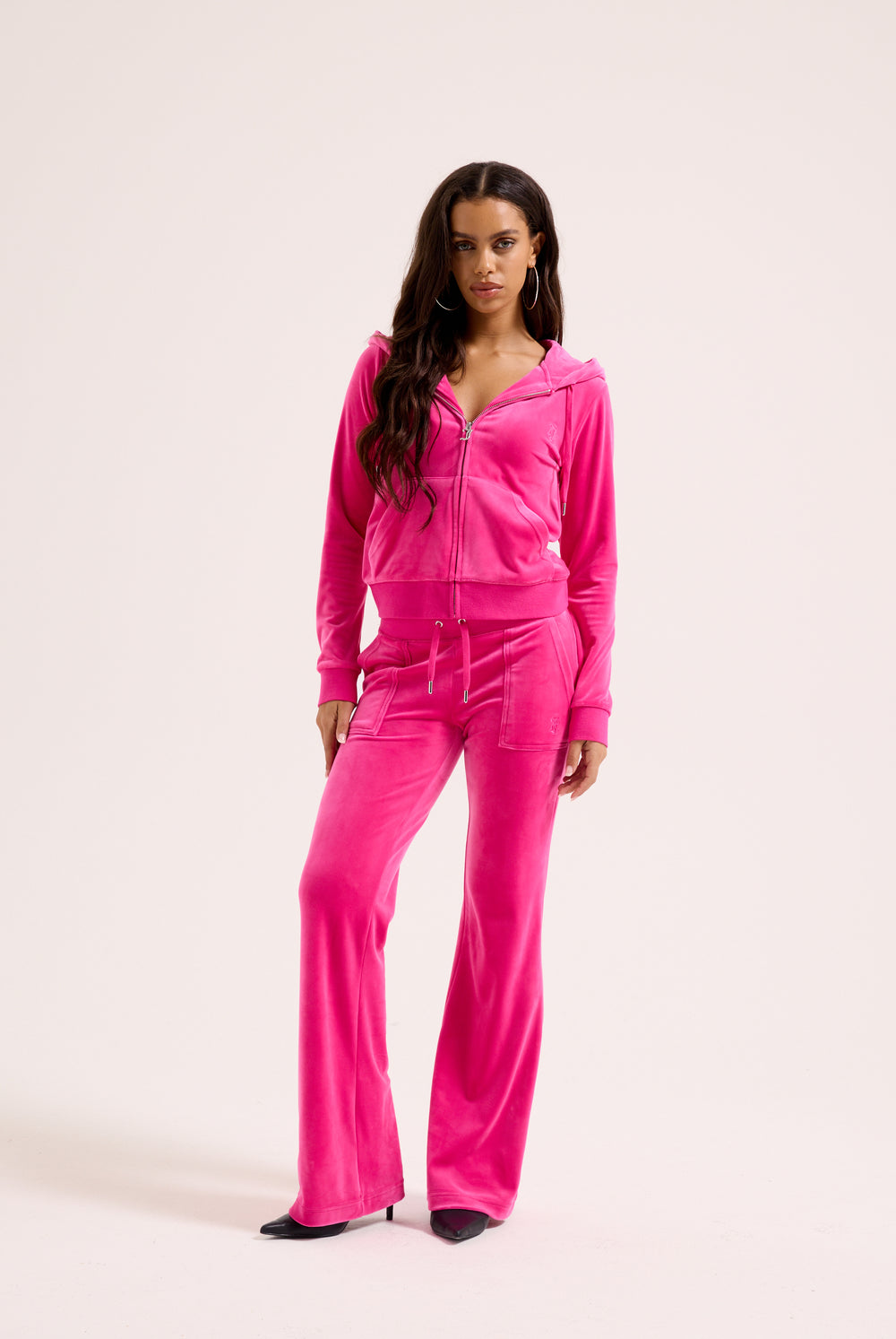 Displays a model wearing the Nostalgia Pink 'Juicy' branded pink crop oversized classic velour hoodie 
