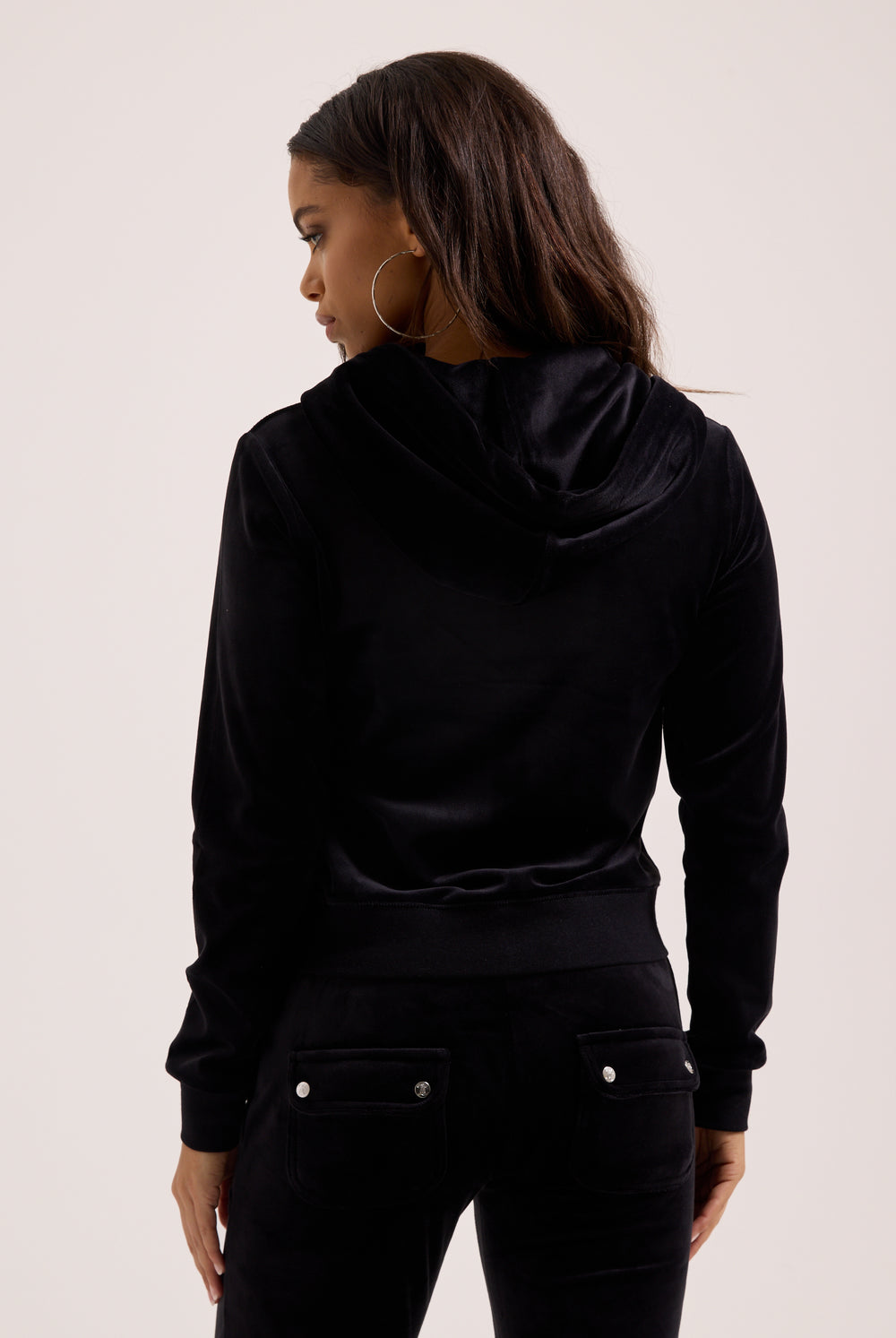 Woman wearing a black hoodie from behind on a light background