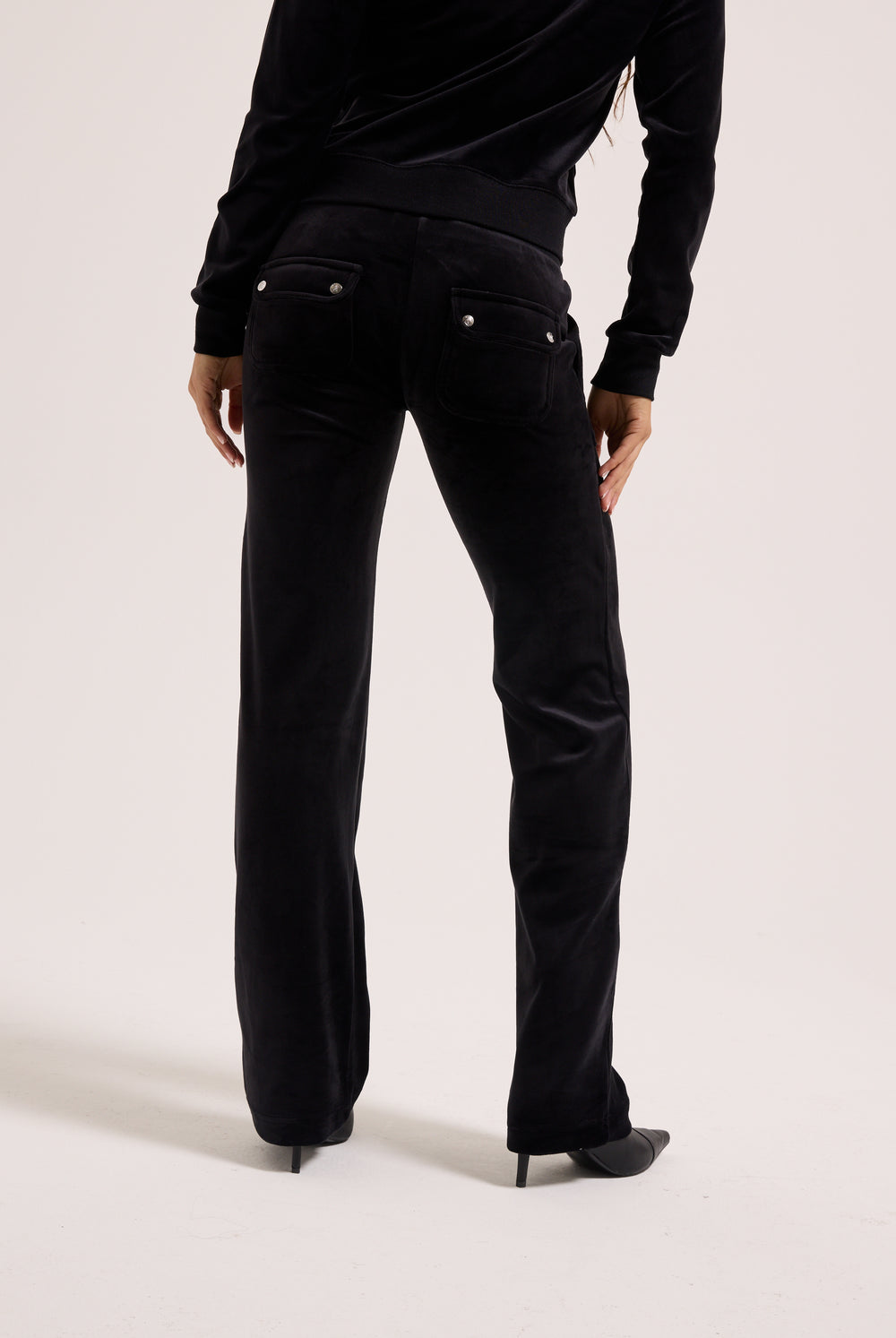Person wearing black pants and a black top on a white background
