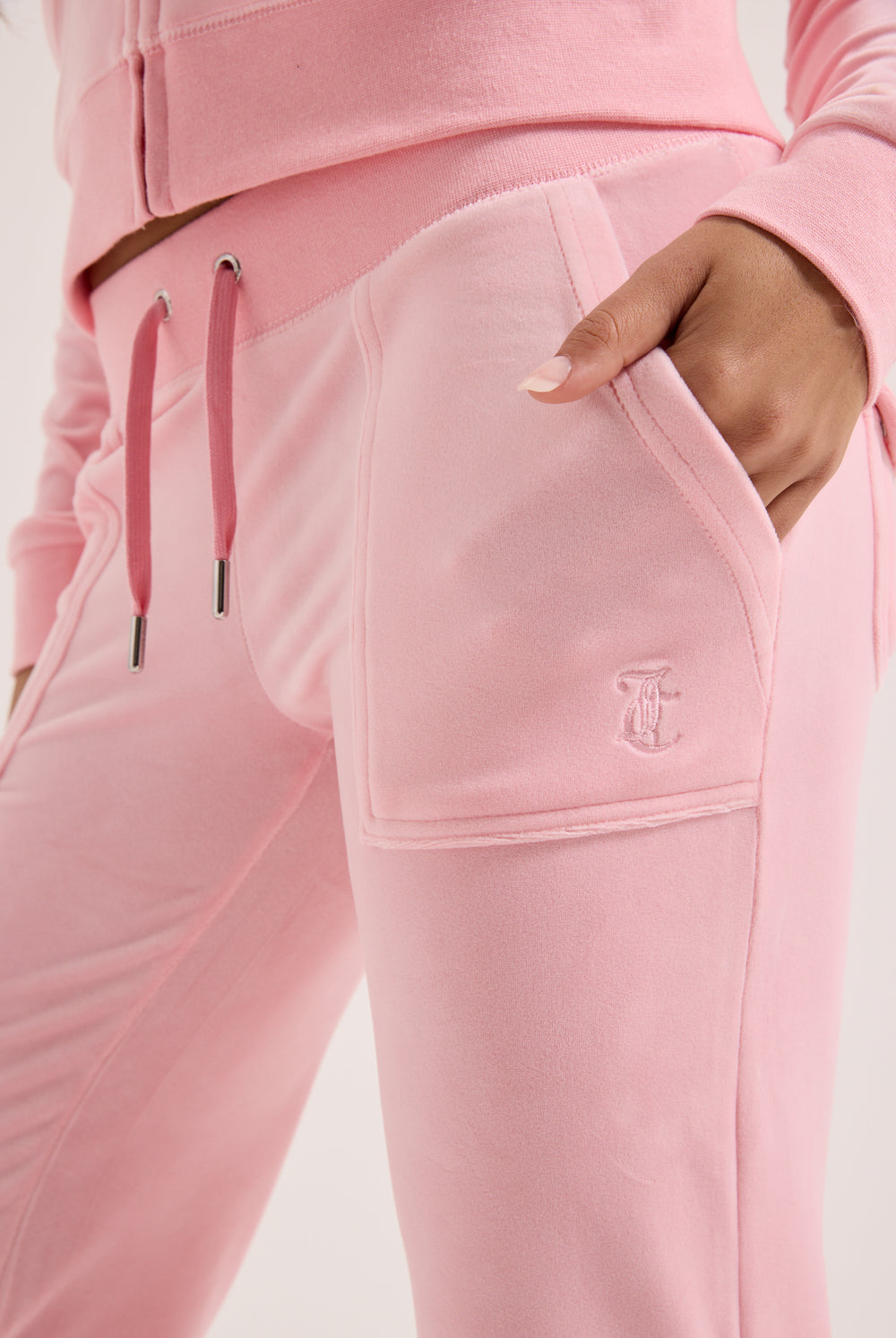 Displays a model wearing the Juicy Pink 'Juicy' branded low rise flare classic velour track pant 