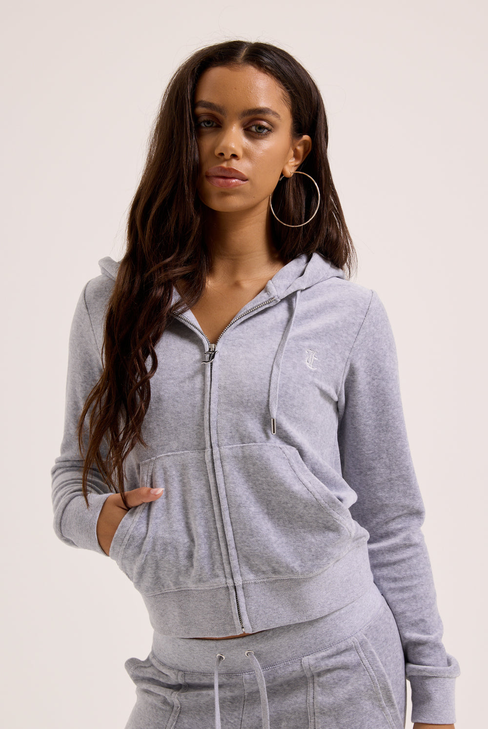 Woman wearing a gray hoodie and pants on a plain background
