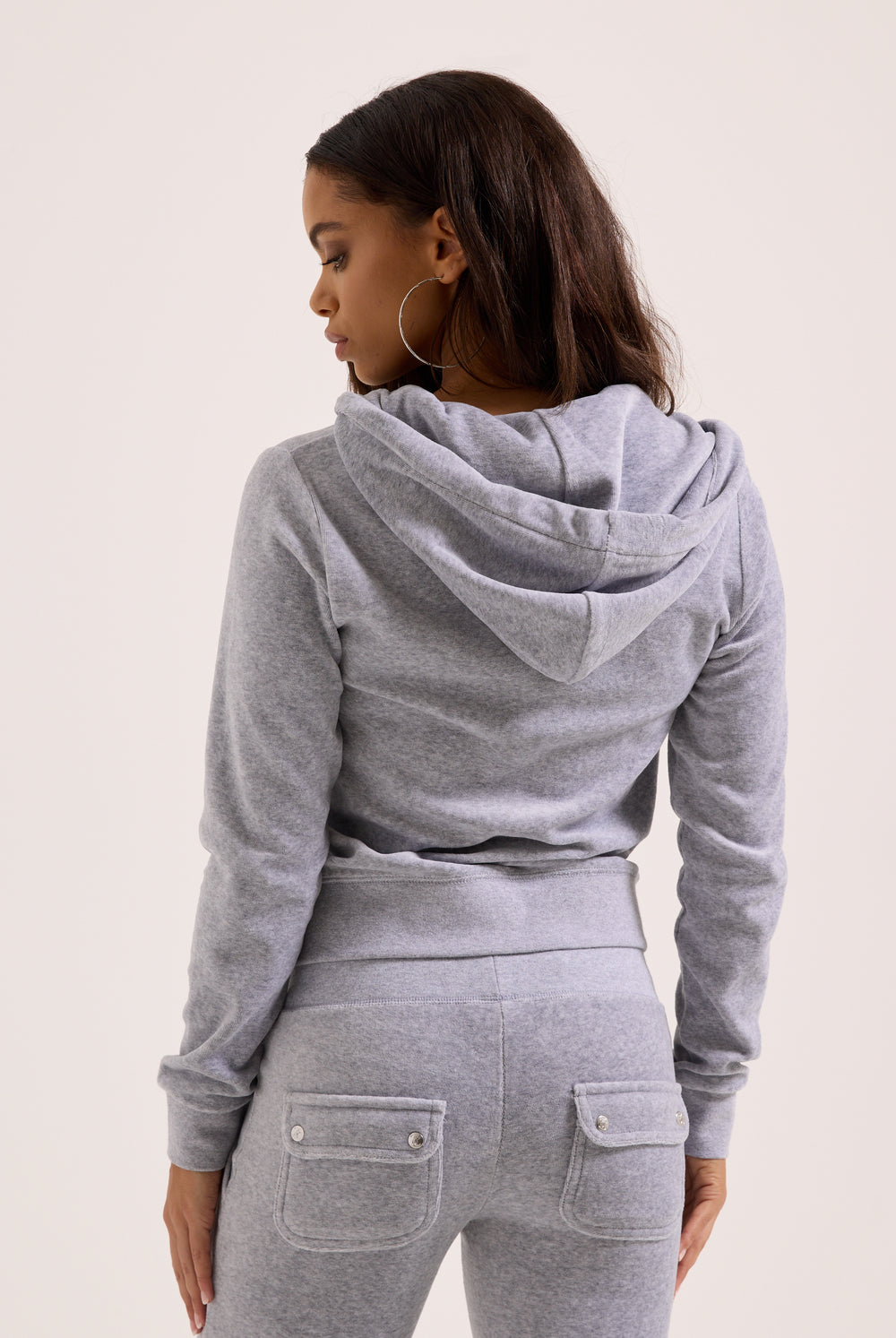 Person wearing a gray hoodie and pants on a light background