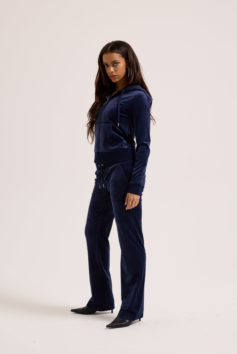 Woman wearing a navy blue velour tracksuit on a white background