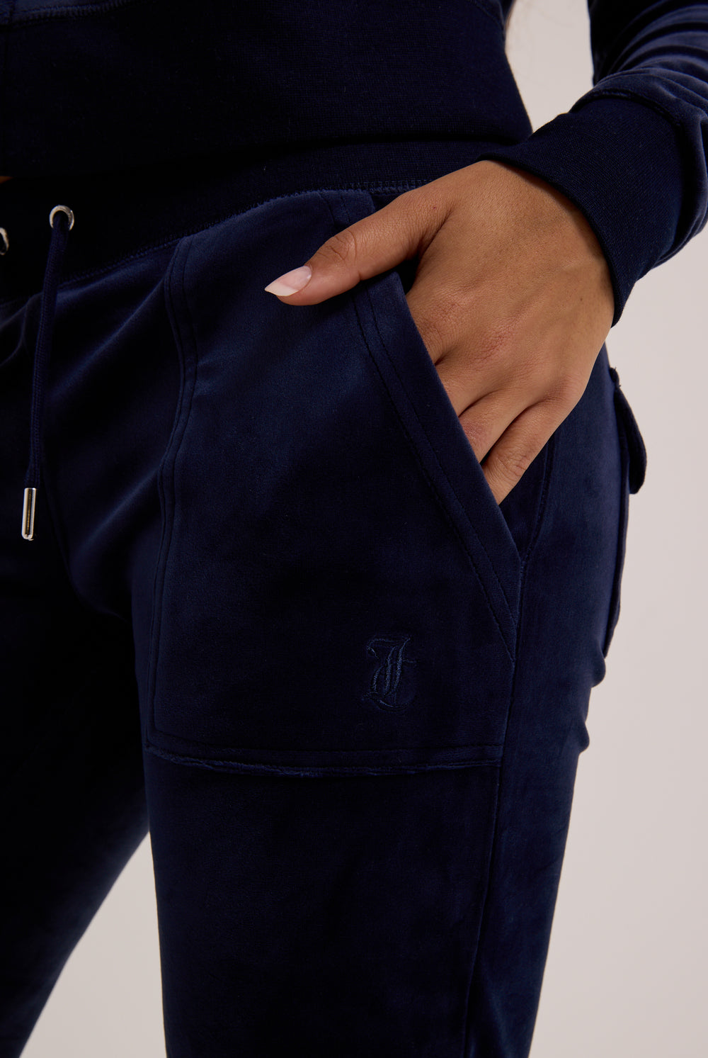 Navy blue tracksuit with a hand in the pocket on a neutral background