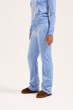 Displays a model wearing the Della Robia classic 'Juicy' branded velour del ray pocketed bottoms 