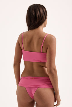 Displays a model wearing the Azalea Pink Roxy and Juicy Couture bandeau bikini top 