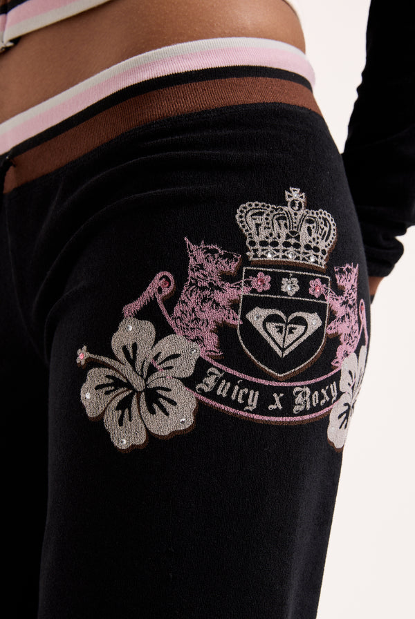 Displays a model wearing the Black Roxy & Juicy Couture Terry towelling og straight  bottoms featuring the juicy x Roxy logo 