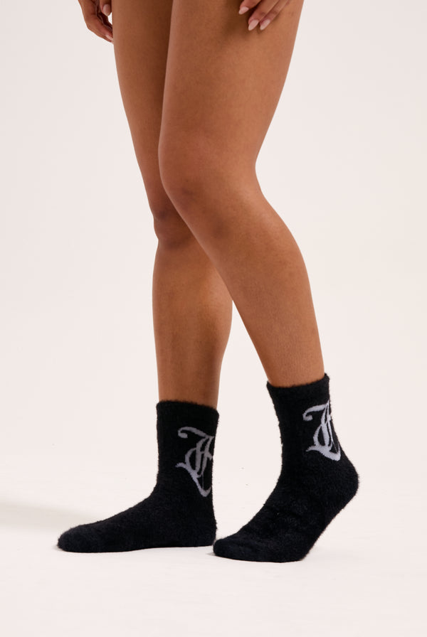 Displays a model wearing the seasonal Black 'Juicy' branded fluffy sock