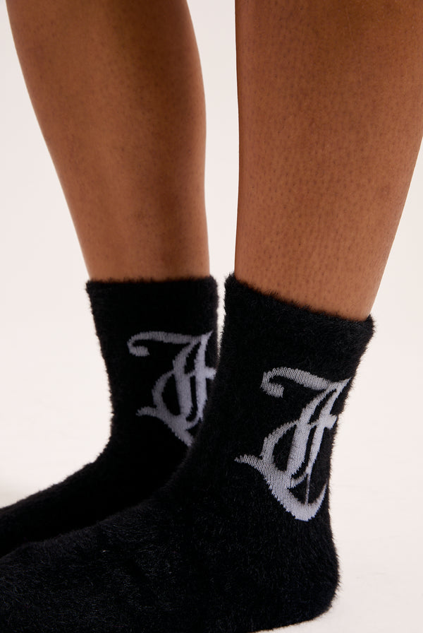 Displays a model wearing the Black seasonal 'Juicy' branded fluffy sock included in the 2 pack 