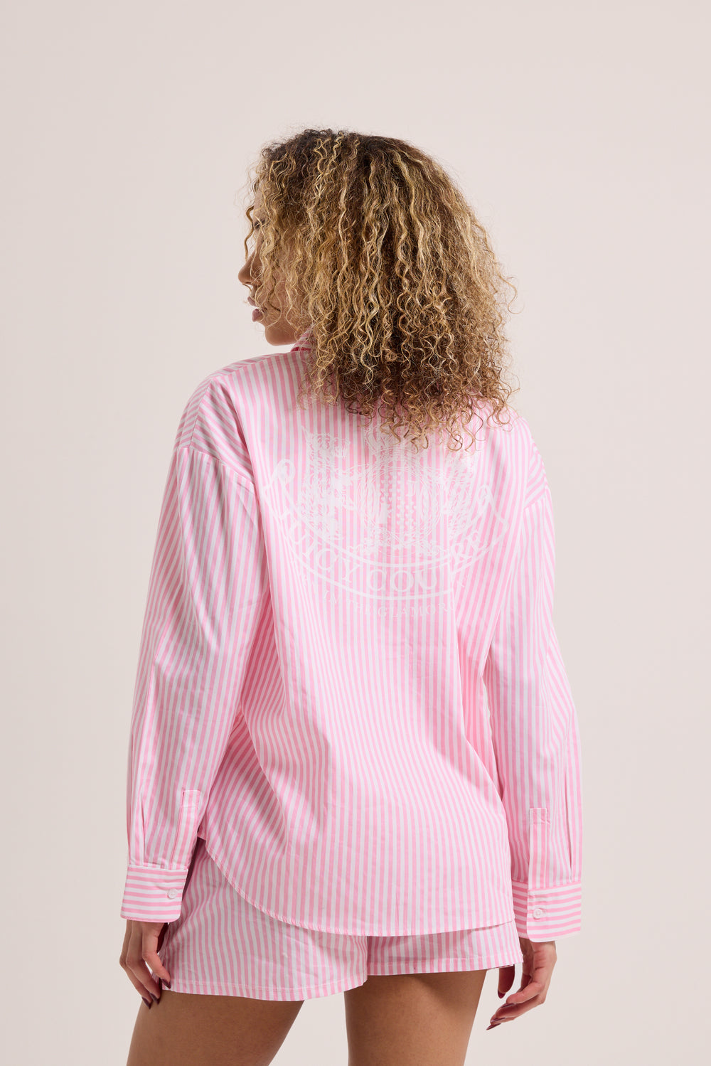 Displays a model wearing the Pink stripe 'Juicy' branded loungewear oversized shirt 