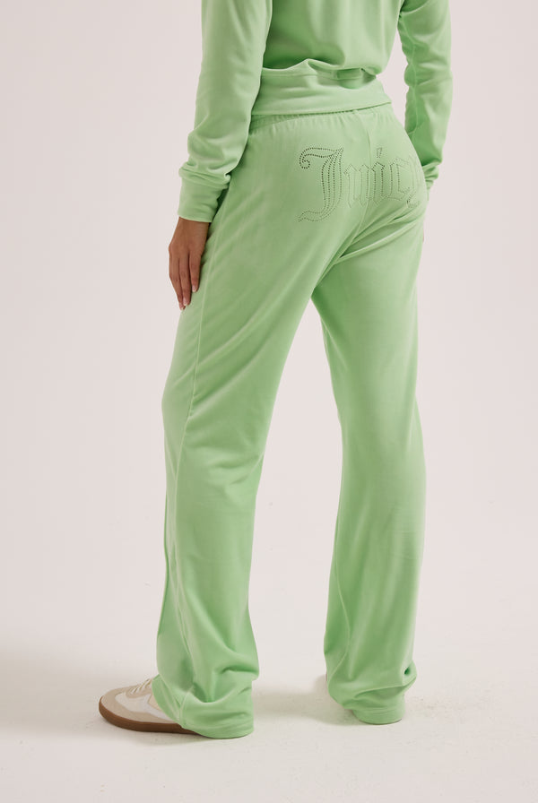 Displays a model wearing the pistachio green outline 'Juicy' branded velour diamanté tracksuit bottom 
