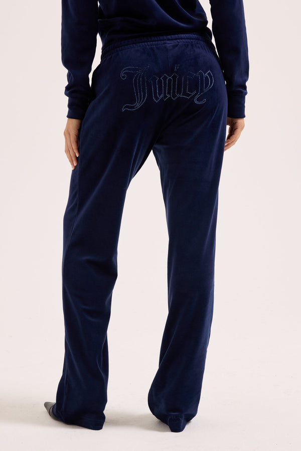 Displays a model wearing the Night Sky outline 'Juicy' branded velour diamanté tracksuit bottom 