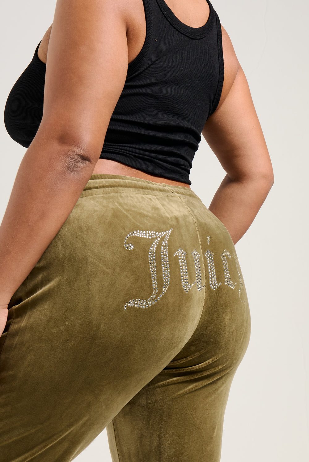 Displays a model wearing the Dark Olive 'Juicy' branded velour diamanté tracksuit bottom