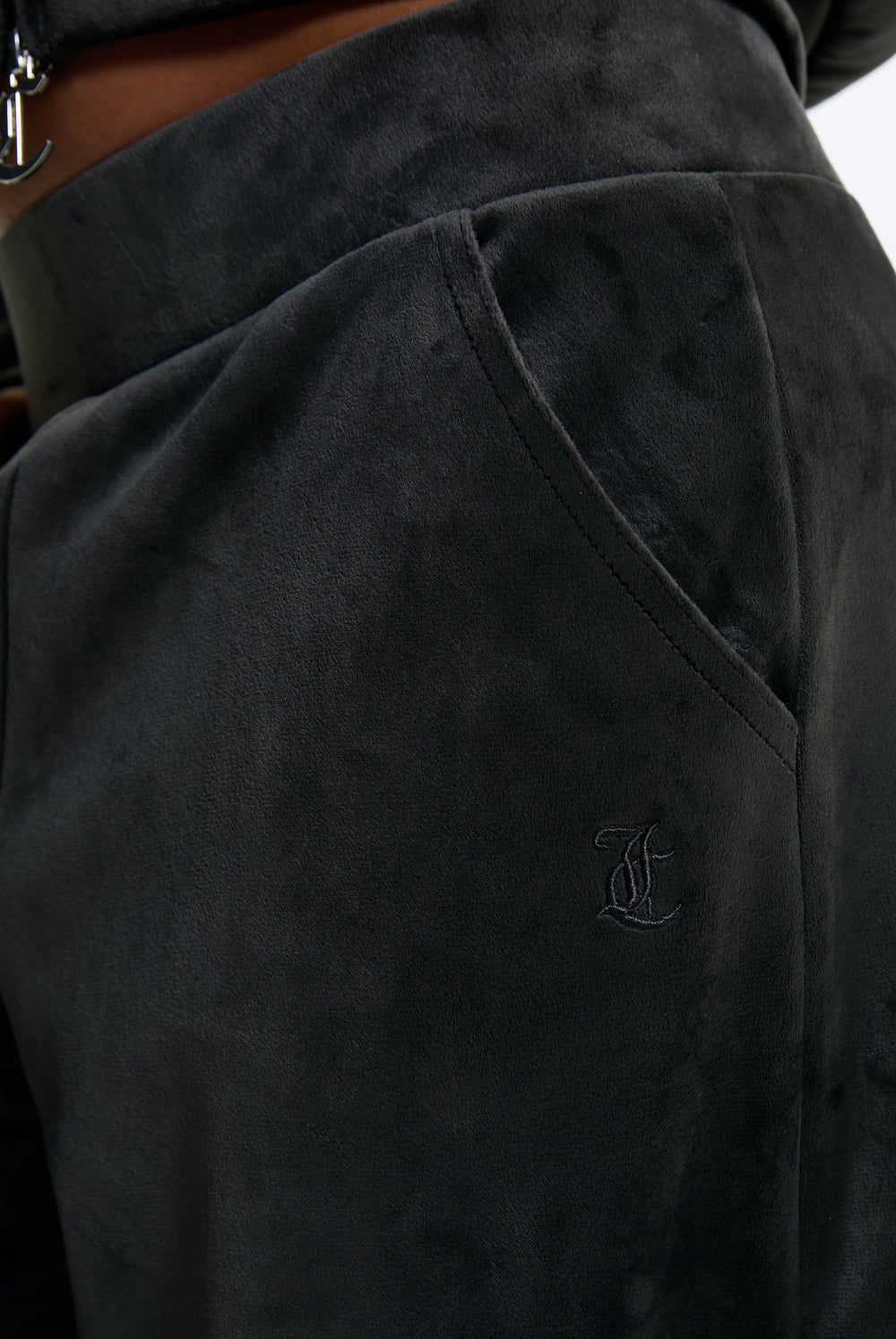 Displays a model wearing the Raven 'Juicy' branded Velour Bonded Tracksuit Bottom featuring the juicy branding 