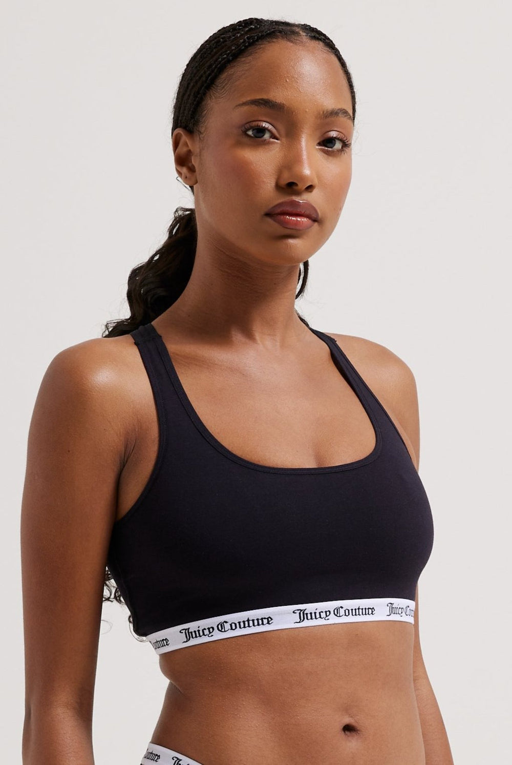 Displays a model wearing the Black 'juicy' branded cotton bralette