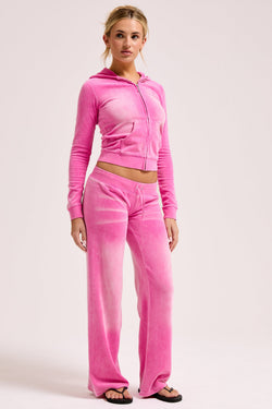Displays a model wearing the Super Pink washed 'Juicy' branded OG straight track pant 