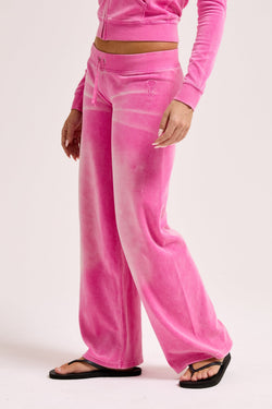 Displays a model wearing the Super Pink washed 'Juicy' branded OG straight track pant 